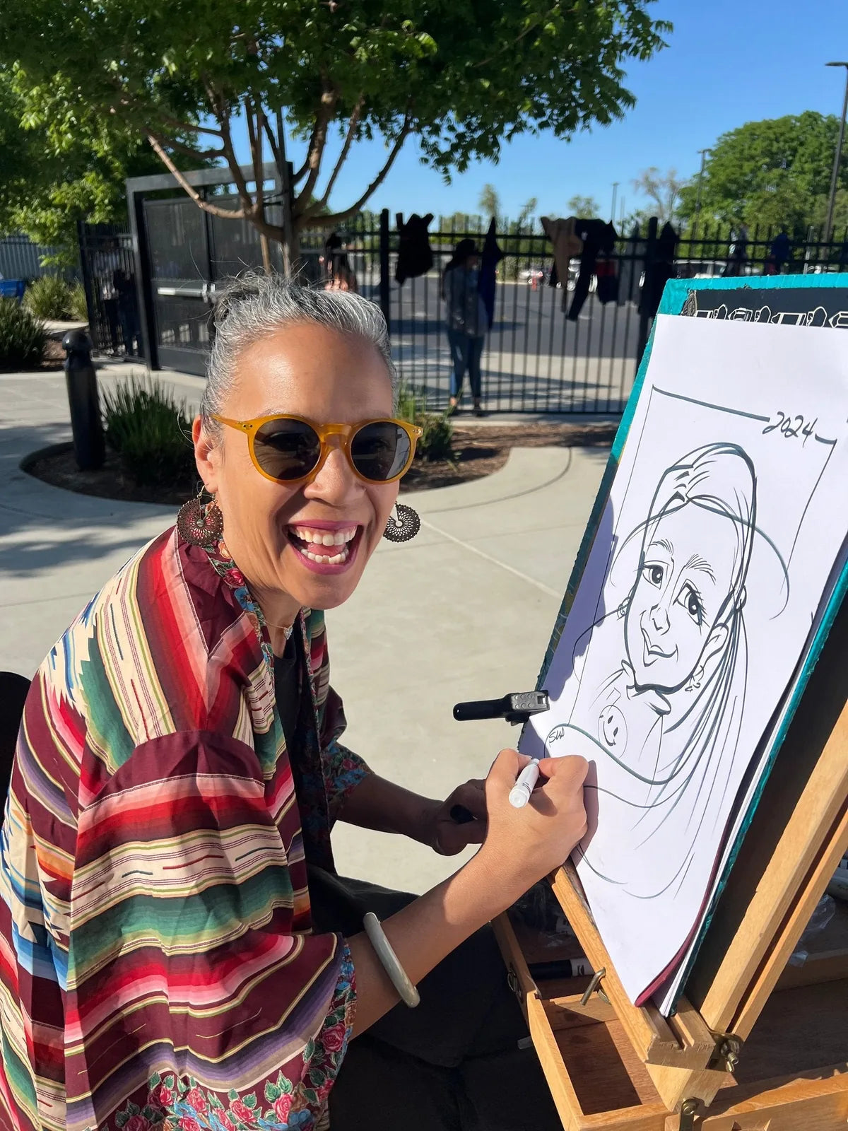 Drawing a guest's portrait on an easel at an outdoor event